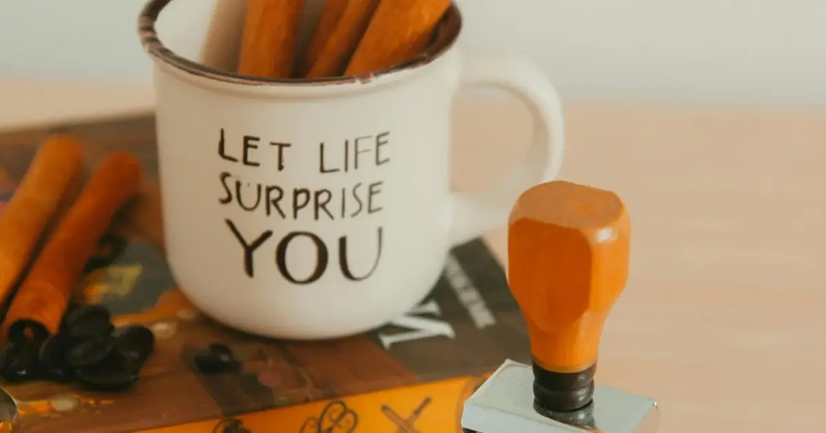 A book and a coffee on a table with a meaningful sentence 'let life surprise you'.