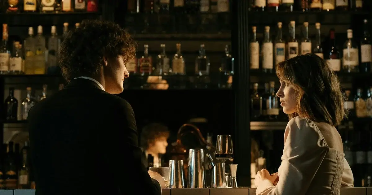 A couple at a bar with a background filled with bottles.