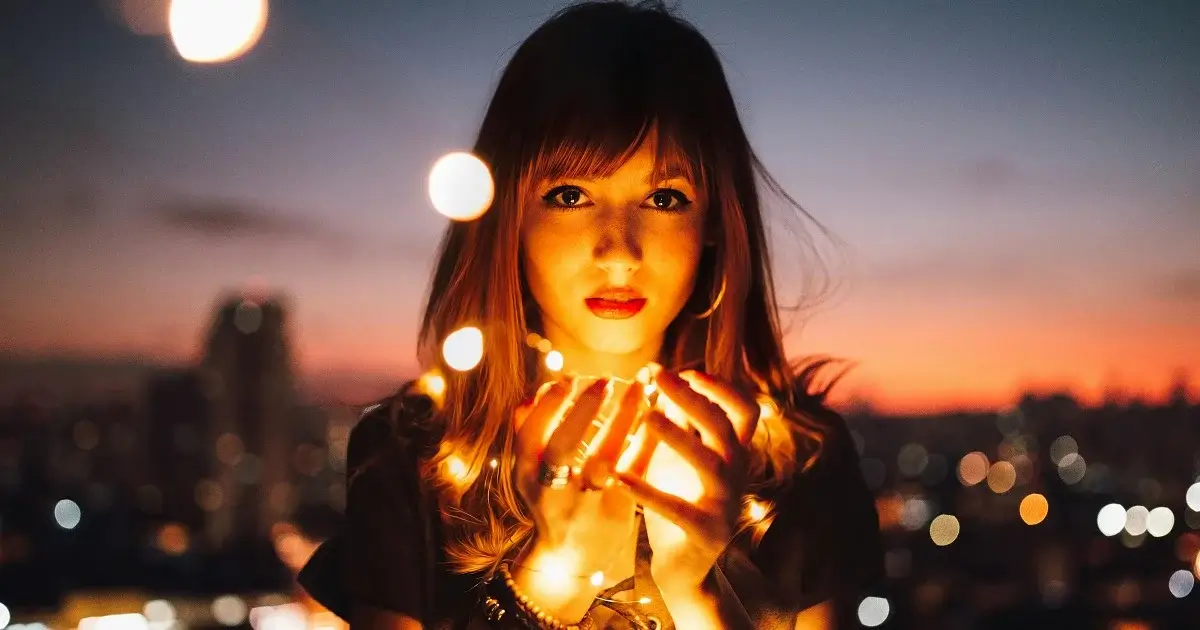 A girl looking into the camera with some balls of light.