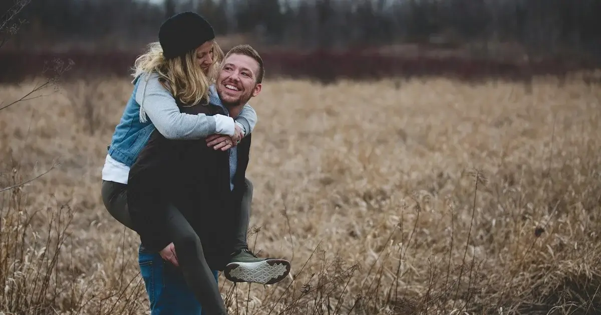 A girl riding the back of her boyfriend.