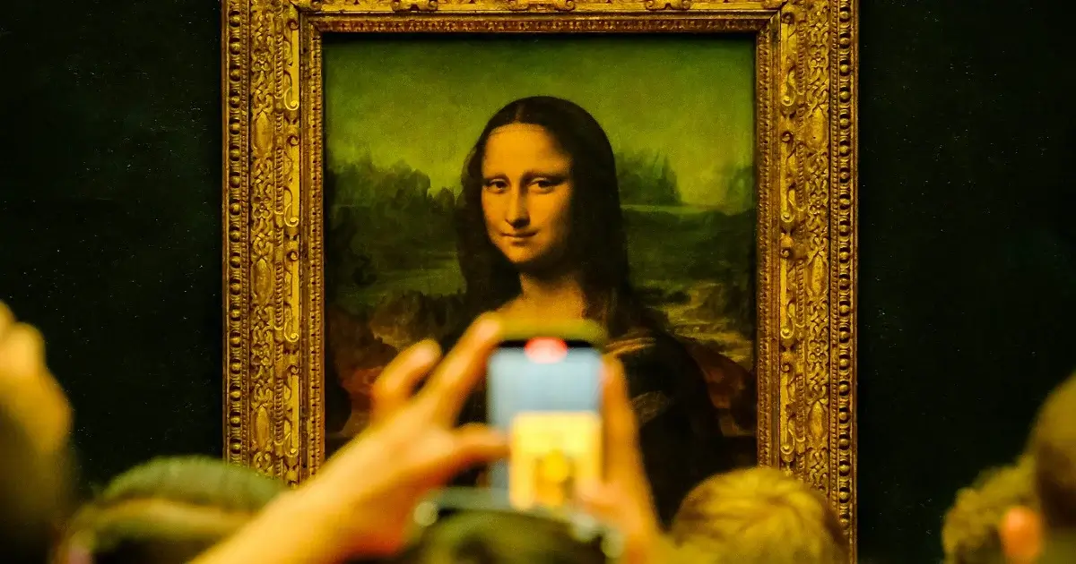 The painting of mona lisa in a gallery been photographed by a crowd of people