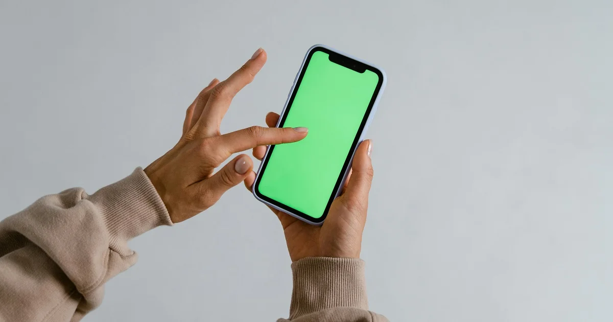 A phone with green screen being swiped upon by a woman